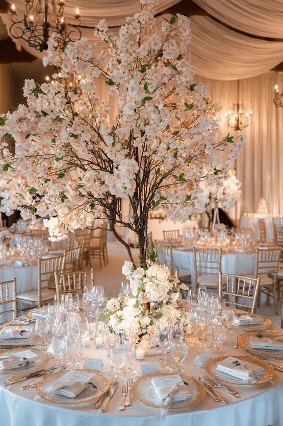a formal wedding reception with faux blooming cherry trees, blooms on the table and candles around for a spring wedding