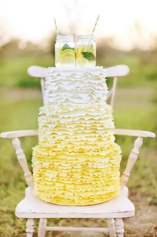 a fun ombre yellow ruffle wedding cake topped with mason jars with lemonade for a rustic wedding
