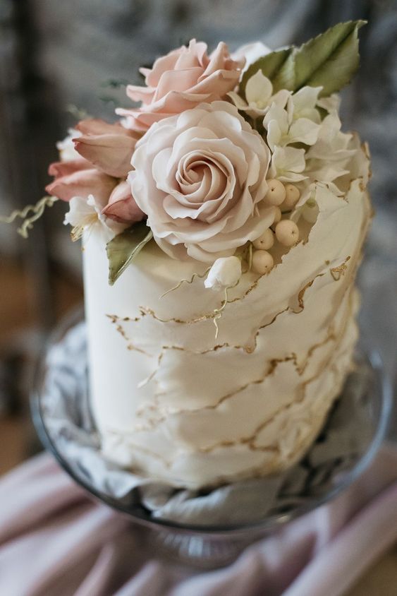 a lovely white ruffle wedding cake with a gold edge and some fresh and sugar blooms on top wows