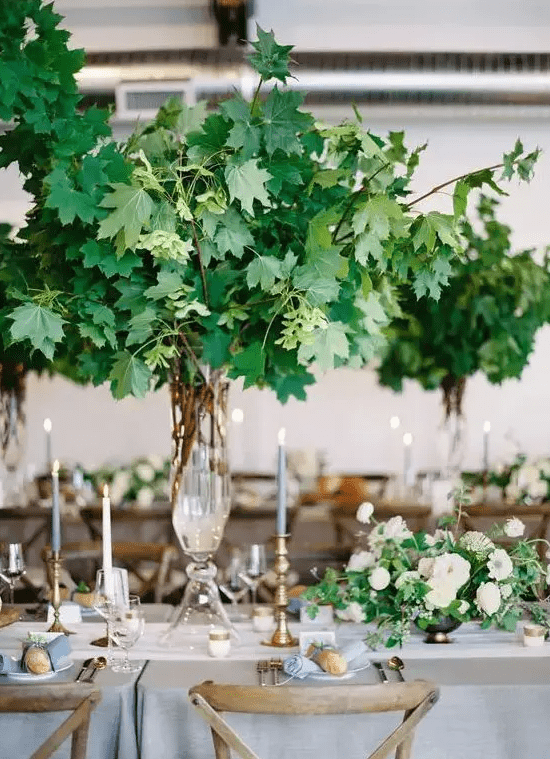 a lush and oversized tall foliage centerpiece is a wow solution that makes indoors feel like outdoors