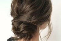 a messy and dimensional low bun with a messy bump on top and some locks down is a stylish and cool idea for a wedding