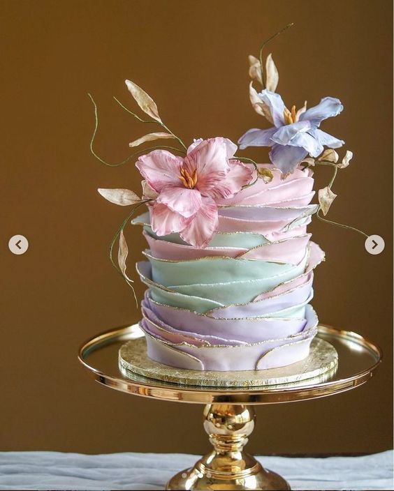 a pastel ruffle wedding cake with a gold edge and pastel blooms is a chic and cool idea for a spring wedding