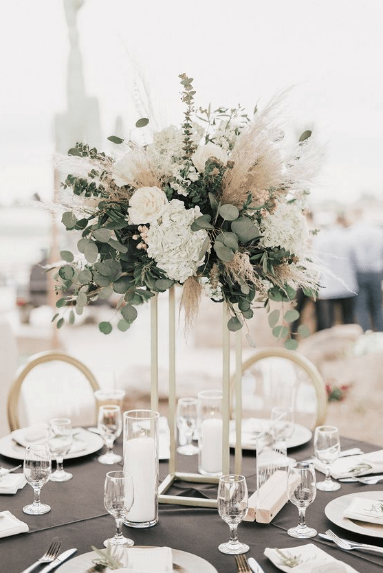 a pretty tall wedding centerpiece of eucalyptus, white blooms and pampas grass for a modern wedding with a boho touch