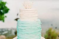 a ruffled beach wedding cake with a white and aqua tier and corals on top