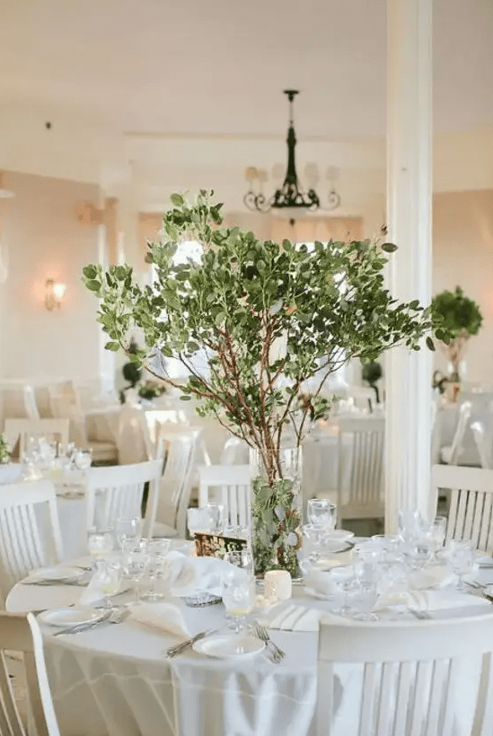 a simple yet stunning centerpiece with fresh greenery on branches is great idea for any season