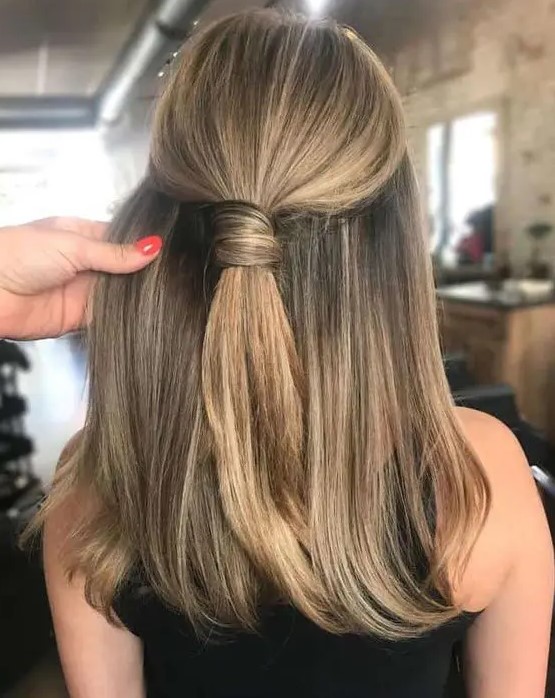 A stylish and cool half updo with a wrapped ponytail on top and straight hair down is a non typical and very modern solution