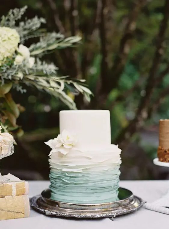 a stylish wedding cake with a white and on ombre green tier, with white sugar blooms is a delicate and chic idea for a spring or summer wedding
