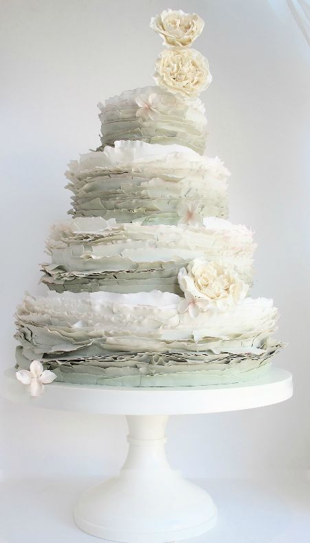 a subtle white and pale green ruffle wedding cake topped with neutral blooms for a spring or summer wedding