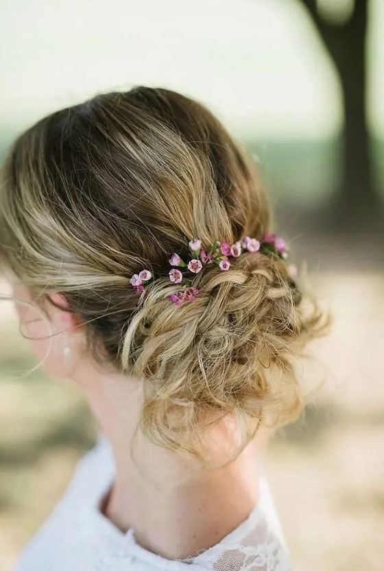 a textural messy updo with braids, a bump and little flowers to add a touch of color