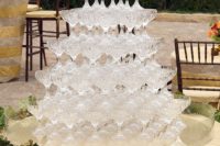 a tower of crystal champagne glasses waits to be filled on a low table decorated with leaves