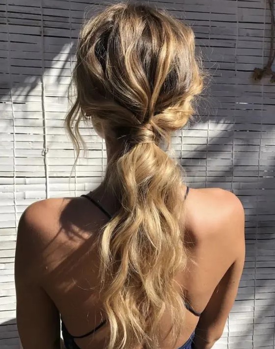 a wavy messy low ponytail with some locks down is great for a casual rehearsal dinner or a casual wedding
