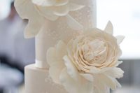 a white pattern wedding cake with ruffles topped with oversized white sugar blooms is a very sophisticated idea