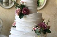 a white ruffle wedding cake decorated with purple blooms and greenery is an elegant vintage-inspired idea