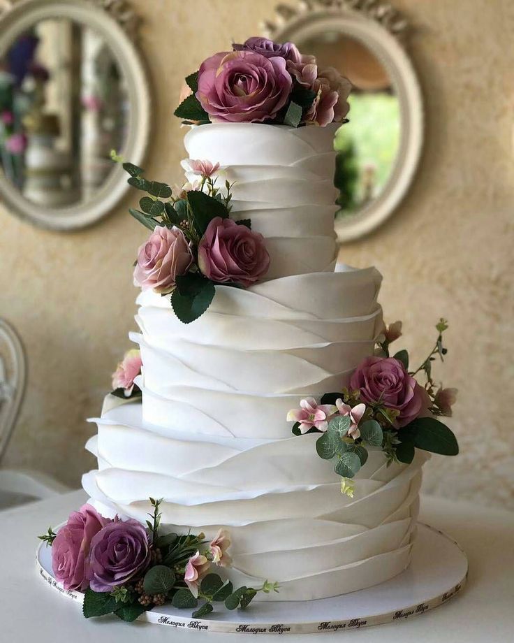 a white ruffle wedding cake decorated with purple blooms and greenery is an elegant vintage-inspired idea