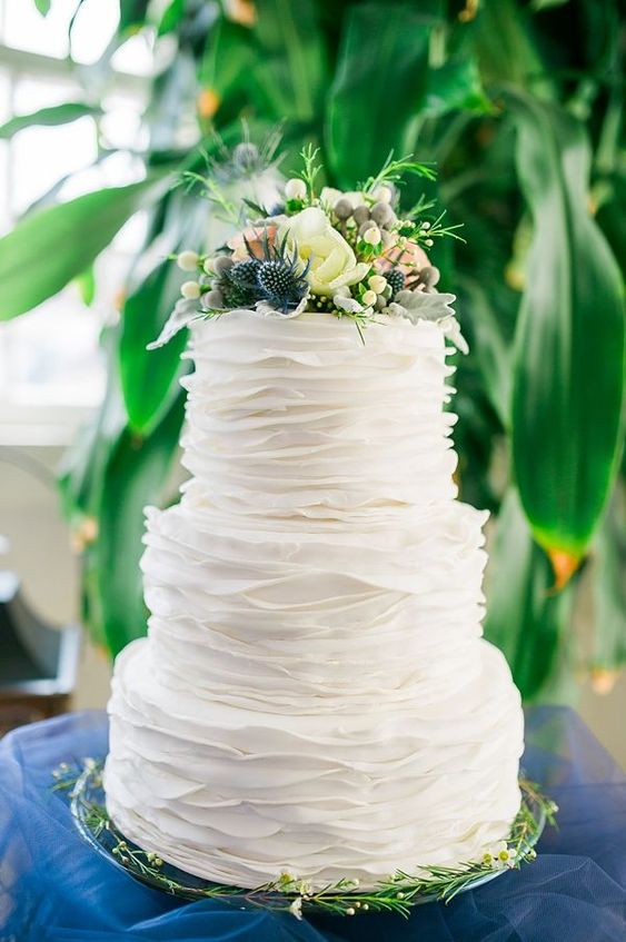 a white ruffle wedding cake topped with fresh blooms, thistles and greenery is a stylish and chic idea for a spring or summer wedding