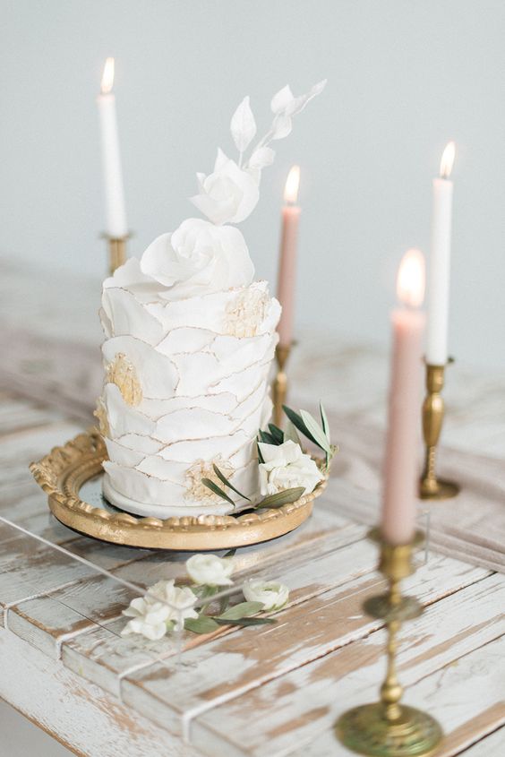 a white ruffle wedding cake with a golden edge and blooms and white sugar blooms on top is amazing
