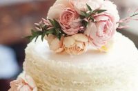 a white ruffle wedding cake with blush blooms and greenery on top is amazing for a classic spring wedding
