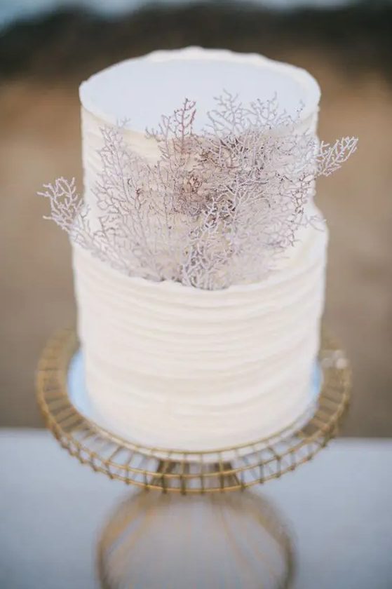 a white ruffled wedding cake decorated with corals is a stylish way to pull of a beach look