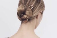 an elegant braided low bun with a sleek top and a large hair pin is a stylish and cool modern hairstyle
