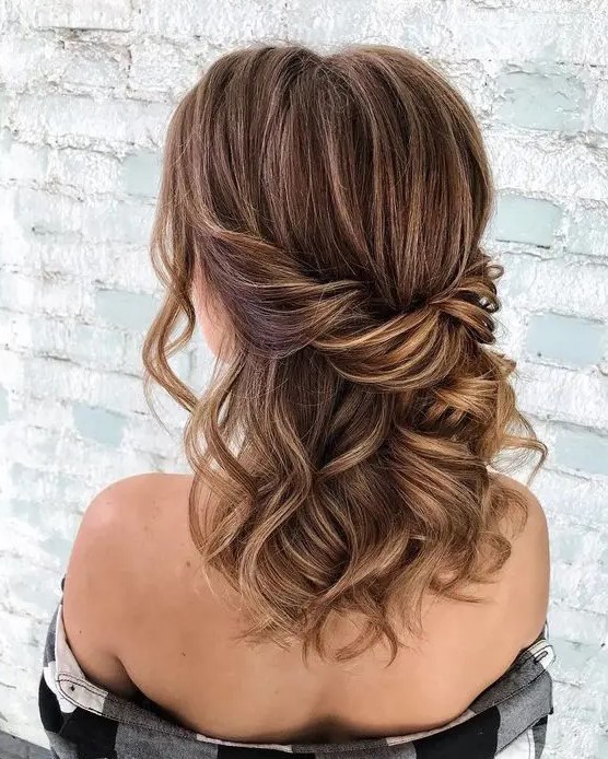 An elegant brown half updo with caramel balayage and a twisted touch plus some waves down and face framing locks