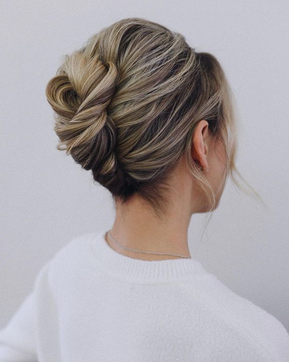 an elegant twisted chignon with a bump on top and some waves down is a cool idea for a refined and more formal wedding