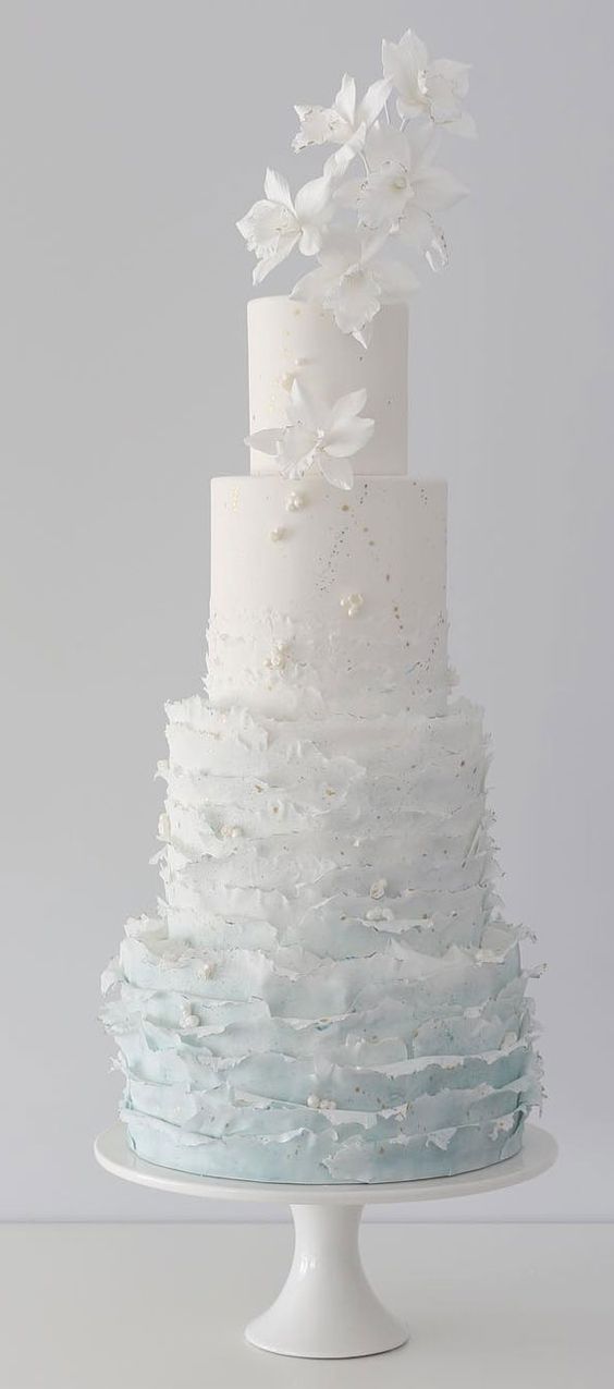 an ombre white to light blue ruffle wedding cake with pearls, sugar blooms and some patterns is a very chic and ethereal idea