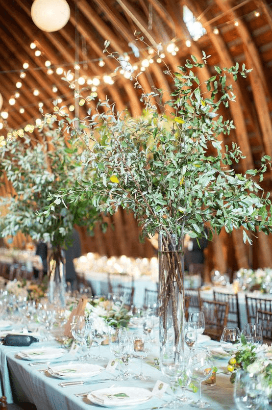 barn wedding centerpieces of tall clear vases with greenery branches look chic and very modern