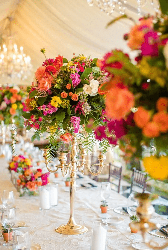 chic tall wedding centerpieces of greenery, hot pink, red, peachy pink, yellow and orange blooms are wow