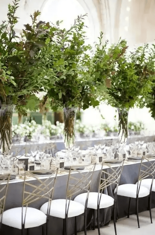 such tall lush textural greenery centerpieces in clear vases create a feeling of outdoors right in your venue