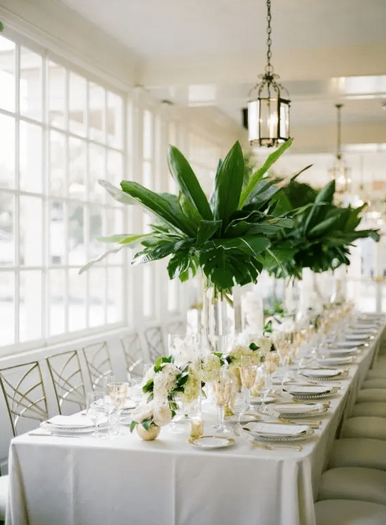 tall centerpieces in clear glass vases with palm leaves are great for a southern or tropical wedding
