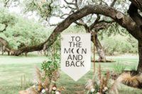 02 The wedding ceremony space was done with a copper arch with a banner, lush florals, greenery, pampas grass and a boho rug