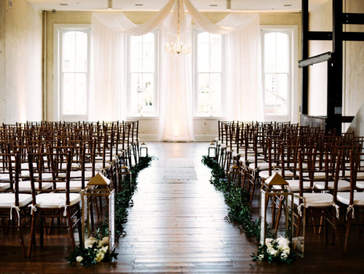 The wedding ceremony space was done with a fabric backdrop, lanterns, florals and greenery