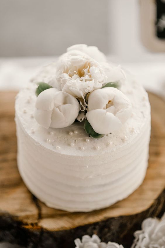 an elegant textural white wedding cake topped with white peonies and edible pearls will never go out of style