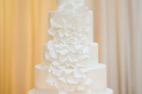 11 a plain white wedding cake decorated with a large white sugar flower, the petals are cascading for a whimsy touch