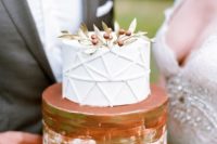 13 a two tiered wedding cake with a geometric layer and a berry topper plus copper leaf for an elegant feel