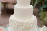 16 a whimsical three-tier wedding cake with sugar flowers and pearls for a vintage feel