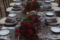 19 a refined reception table decorated with a grey tablecloth and menus, a burgundy table runner, napkins and flower centerpieces