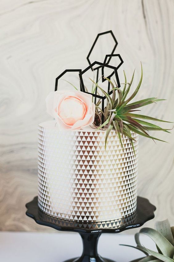 a geometric black and white wedding cake with black hexagon toppers, air plants and a pink blooms for a chic look
