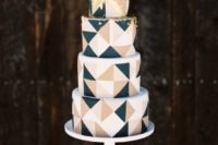 23 a modern geometric wedding cake with white, beige and black triangles and gold leaf on top to combine two trends in one
