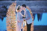 23 a nature-inspired wedding backdrop of two wooden fern leaves decorated with greenery and with candles around