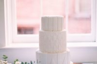 26 an all-white wedding cake with unique frosting textures, all different for each tier is a modern and fresh idea