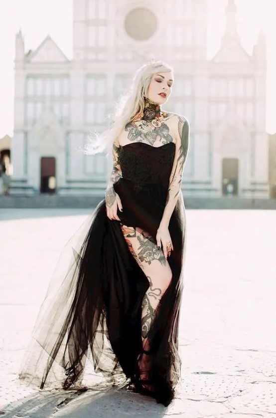 a black strapless wedding dress that show off the bride's tattoos on the neck, chest, shoulders and arms plus on the leg