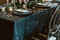 a chic NYE wedding tablescape with a teal sequin tablecloth, black candles, bold blooms and chic cutlery and plates