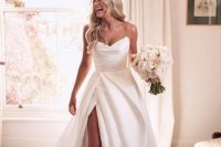 a classic glam strapless wedding dress with a draped bodice and a pleated skirt, a thigh high slit and a train is amazing