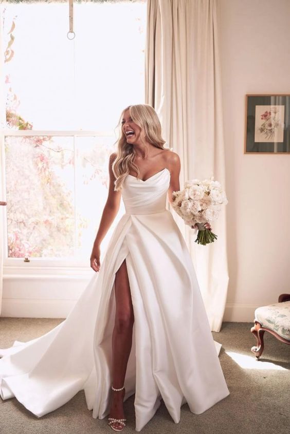 a classic glam strapless wedding dress with a draped bodice and a pleated skirt, a thigh high slit and a train is amazing