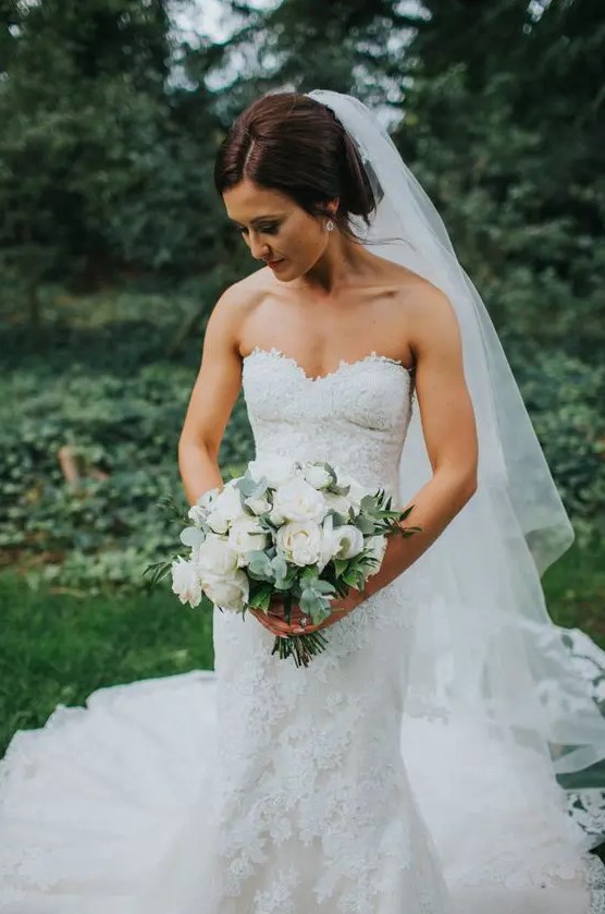 a classic lace strapless mermaid wedding dress with a train and a cathedral veil are a chic and refined combo for a romantic bride