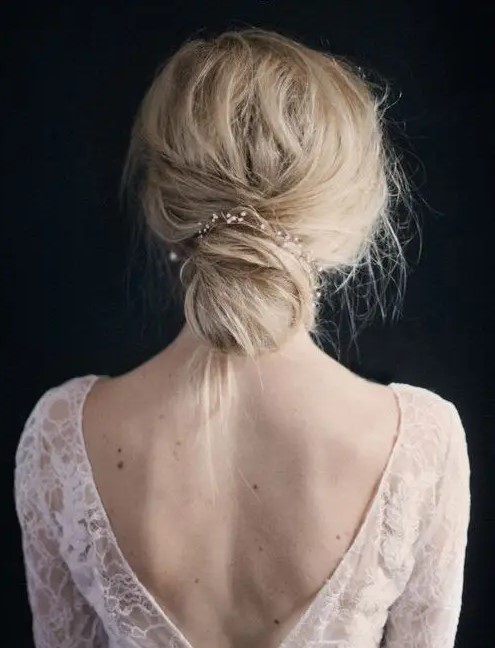 a delicate and romantic wedding low bun with a cute pearly hair vine and a messy touch