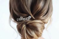 a dimensional low bun with a volumious top and a loose bun plus a rhinestone hairpin is lovely