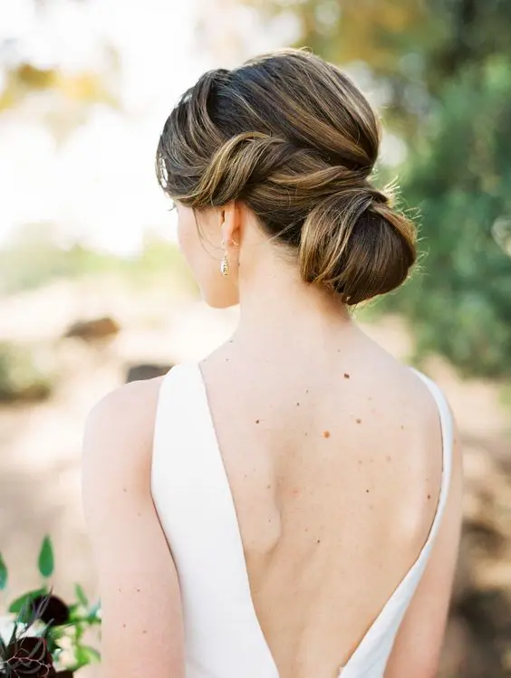 a formal and elegant low bun with a bump on top and waves around the face is a chic and cool idea