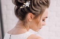 a glam loose top knot with a bump and a floral hair piece is a chic and catchy hairstyle idea